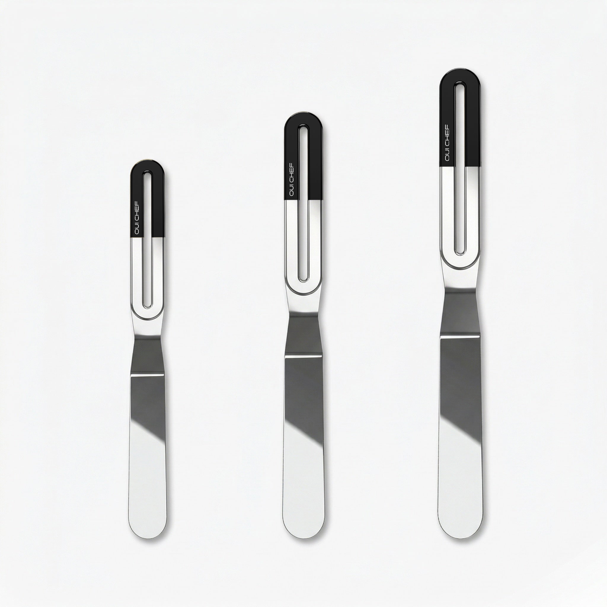 Three stainless steel offset palette knives of increasing size, each with a sleek metal blade and a gloss black top ergonomic handle labeled “OUICHEF,” arranged side by side on a light background.