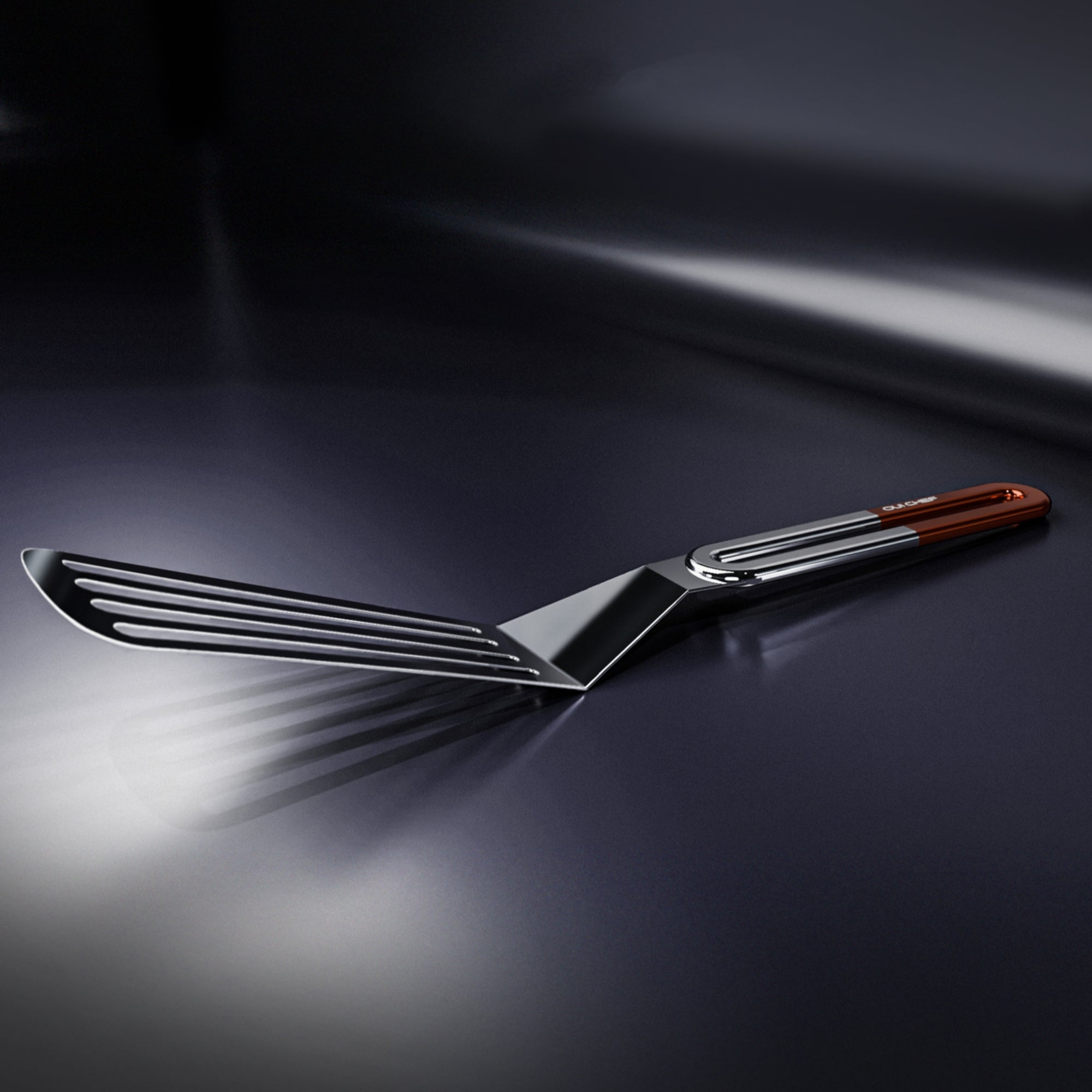 A 3D model image of a stainless steel slotted spatula with a copper coloured handle with "OUI CHEF" logo engraved on it and sitting against a dark background.