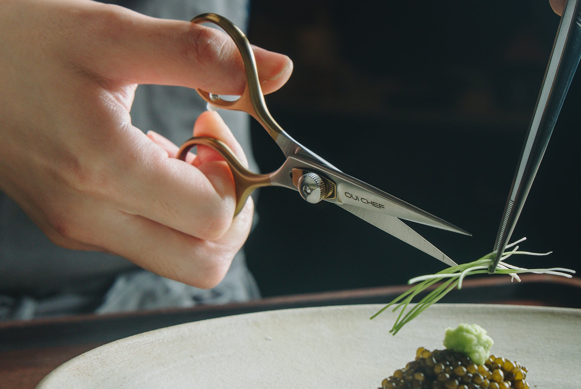 Chef trimming garnish using Oui Chef SuperSharp Scissors and straight tweezers