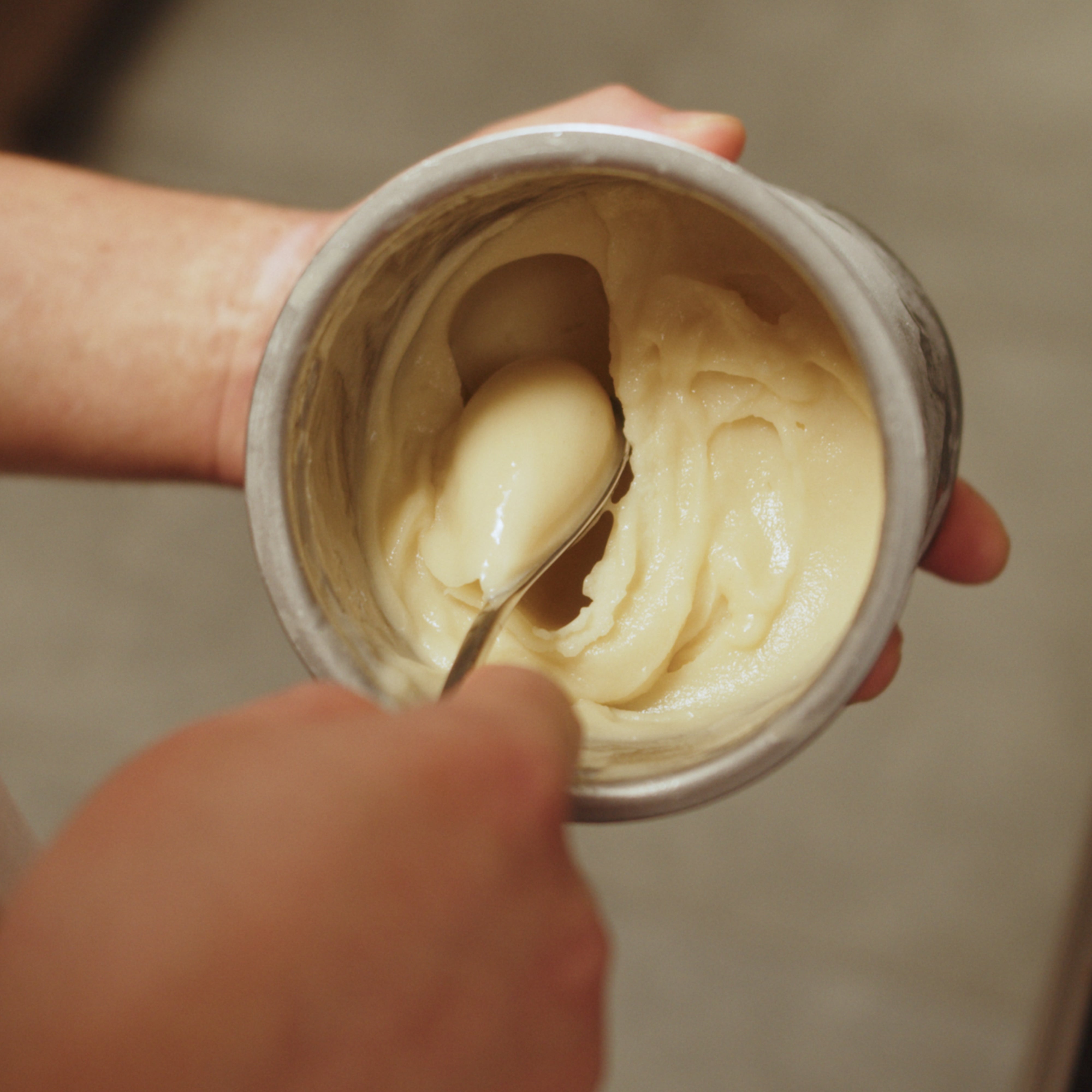 Vanilla ice cream being scooped from a pacojet with a small stainless steel rocher spoon.
